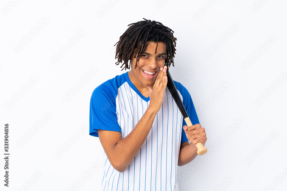 Young African American man playing baseball over isolated white background whispering something Young African American man playing baseball over isolated white background whispering something