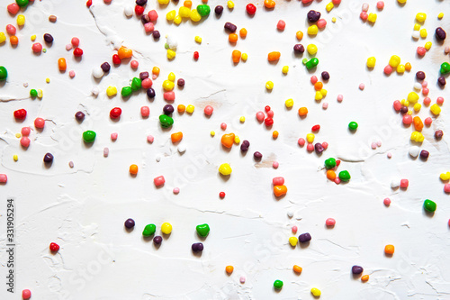 Rainbow colored candy sprinkled on a white background