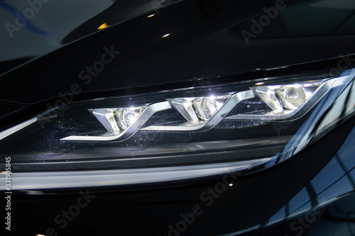 Luminous headlight on a new car in the showroom