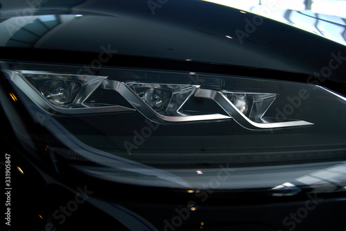 Luminous headlight on a new car in the showroom © Александр Гаврилычев