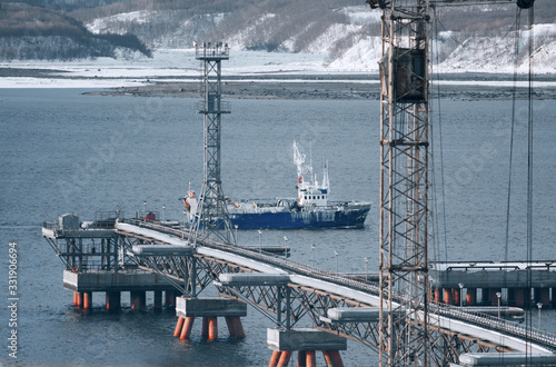 Tug boat is underway on Kola Bay, Murmansk. Production process in the sea. The pipeline equipment in industry