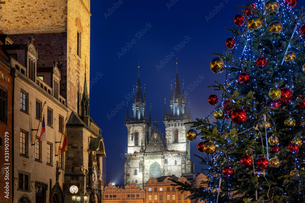 Fototapeta premium Blick zur Marienkirche am alten Dorfplatz in Prag mit beleuchtetem Weiihnachtsbaum und Weihnachtsmarkt zur Adventszeit, Tschechische Republik
