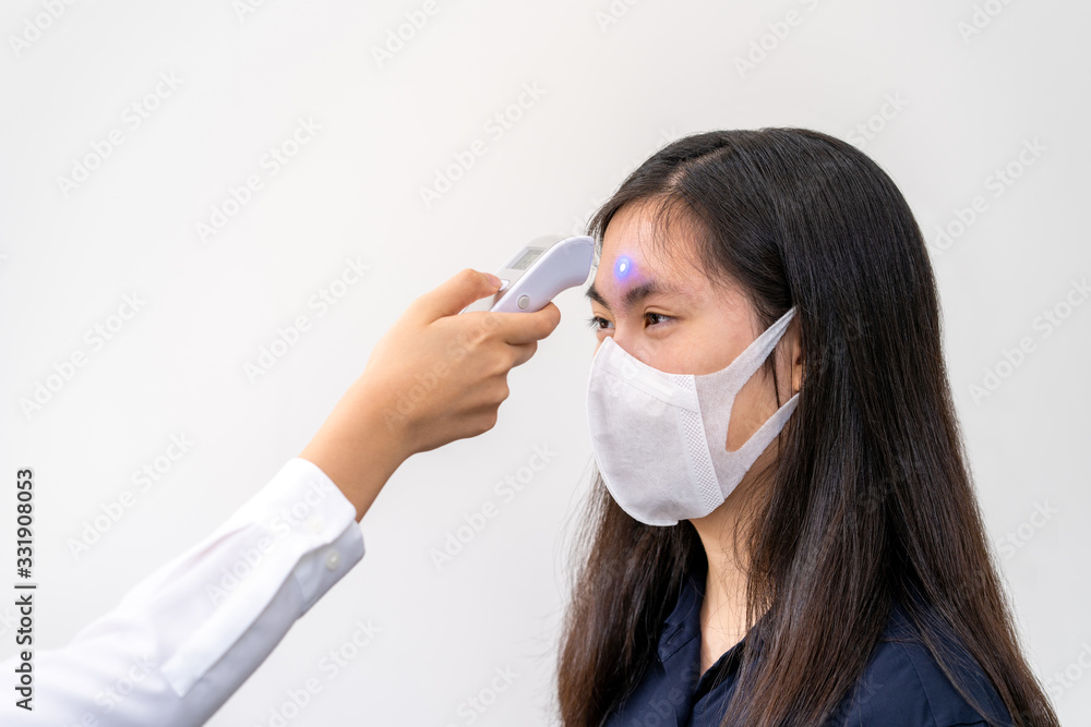 Young Asian woman wearing N95 mask, getting her temperature check Young Asian woman wearing N95 mask, getting her temperature check