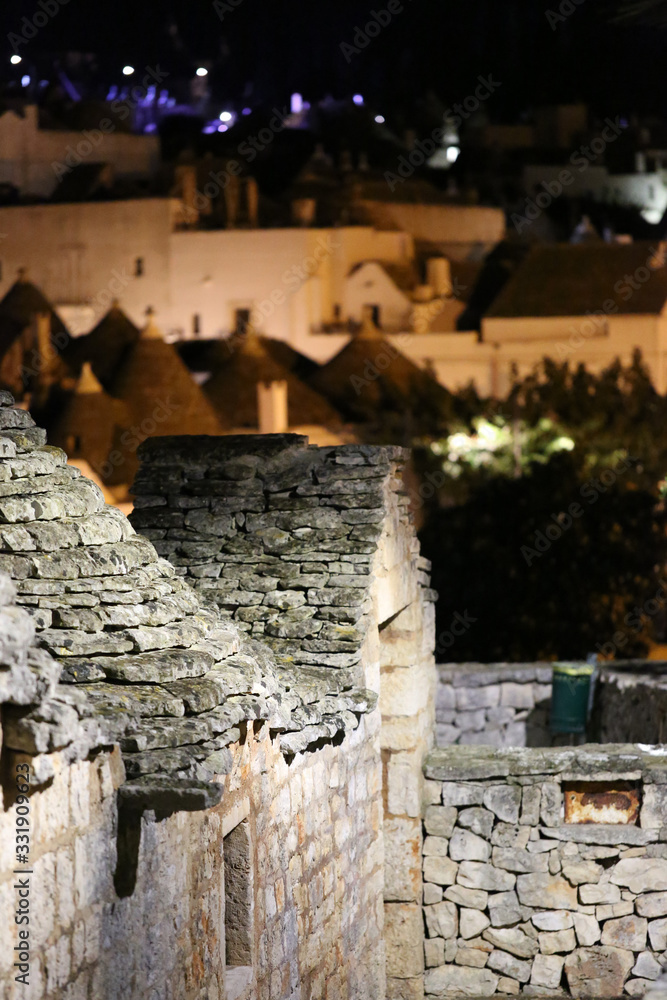 Cityscape of Alberobello; the trulli UNESCO world heritage town with unique stone walls, coned roofs, whitewashed housed during sunset evening, .
