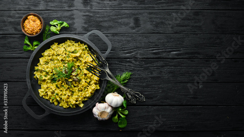 Pasta with pesto sauce, instant cooking in a frying pan. Top view. Free space for your text. Rustic style.