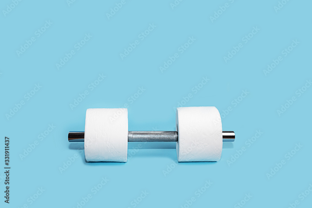 Obraz premium Concept of toilet paper and dumbbell for home quarantine from coronavirus.