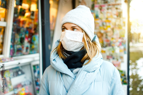 Young woman in medical mask stands next to store in city © snedorez