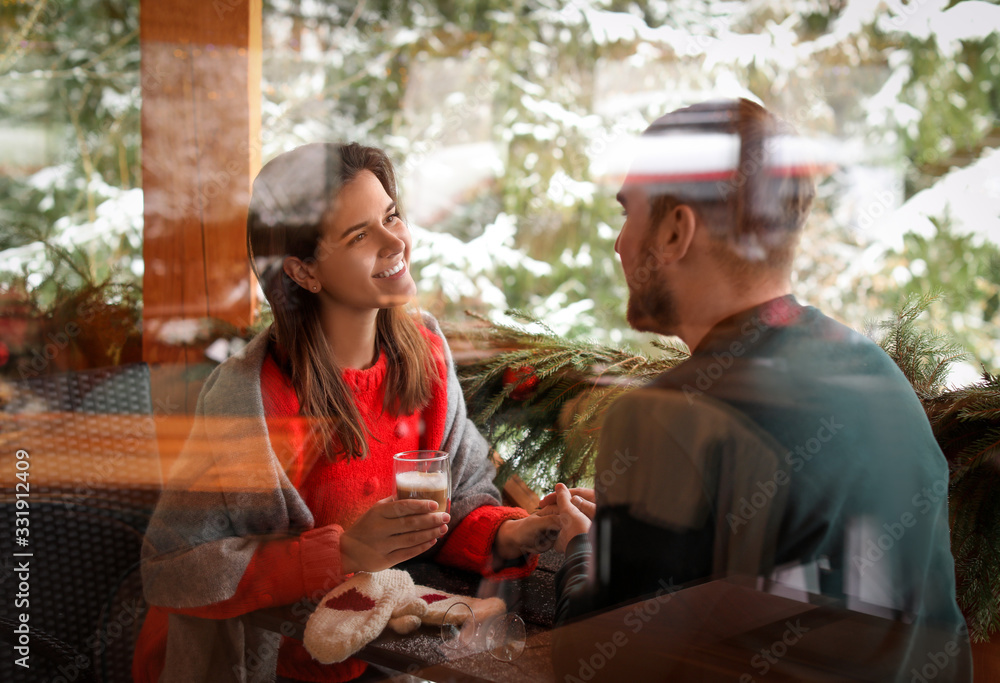 Lovely couple at table in cafe, view through window. Winter vacation Lovely couple at table in cafe, view through window. Winter vacation