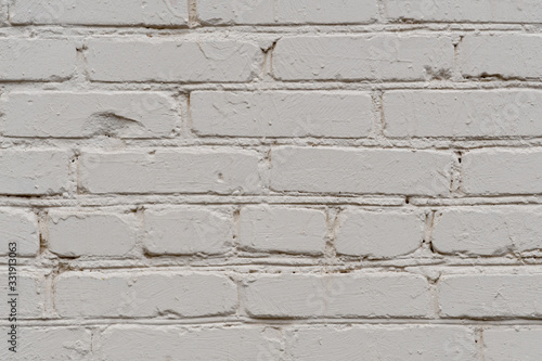 Fragment of roughly painted white brickwork of a wall of an old building in natural light. Close-up. Texture. Background.