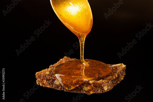 Liquid honey flowing on the sliced rye bread