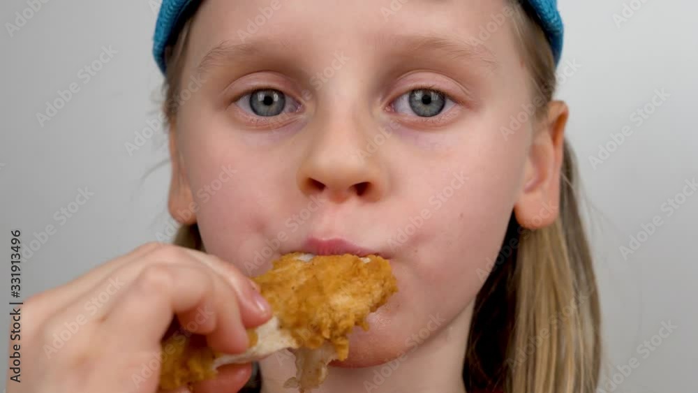Close-Up of a Hungry Child Eating a Delicious Chicken with a Crispy Fried Crust. The Fast-Food Concept Close-Up of a Hungry Child Eating a Delicious Chicken with a Crispy Fried Crust. The Fast-Food Concept
