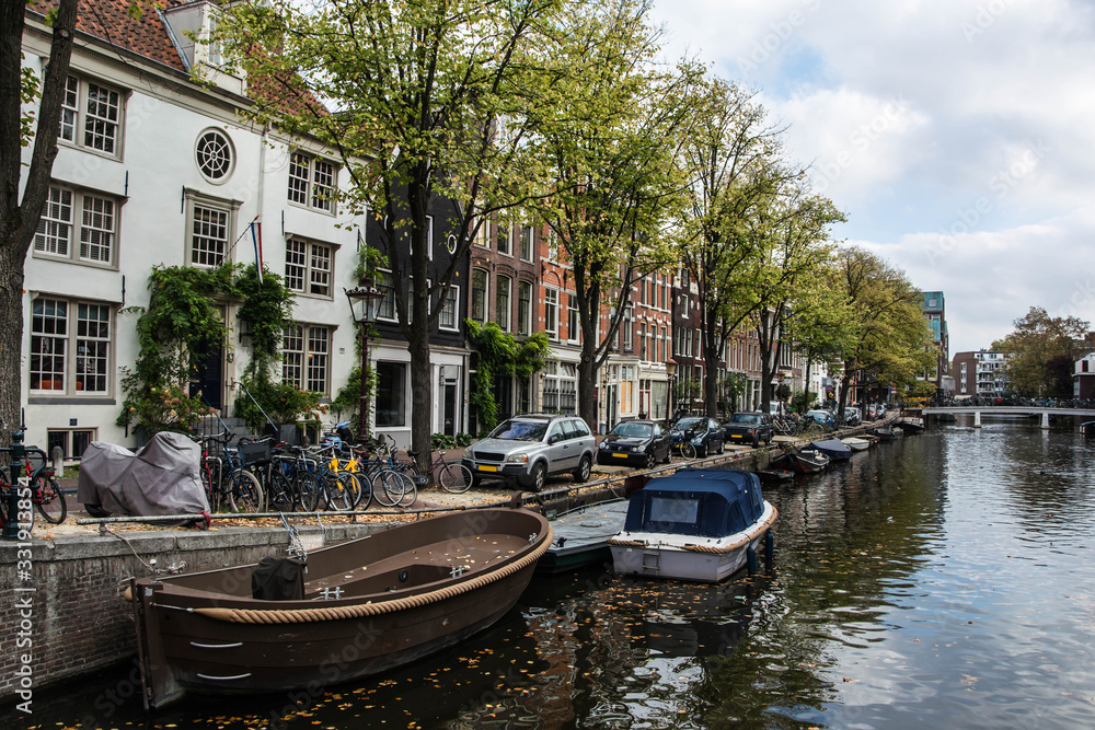Cityscape of Amsterdam. Dutch city architecture. Modern exterior of buildings. Parking near the canal. Boats.
