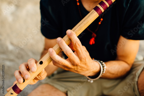 Man's hands playing indian flute bansuri, close up photo