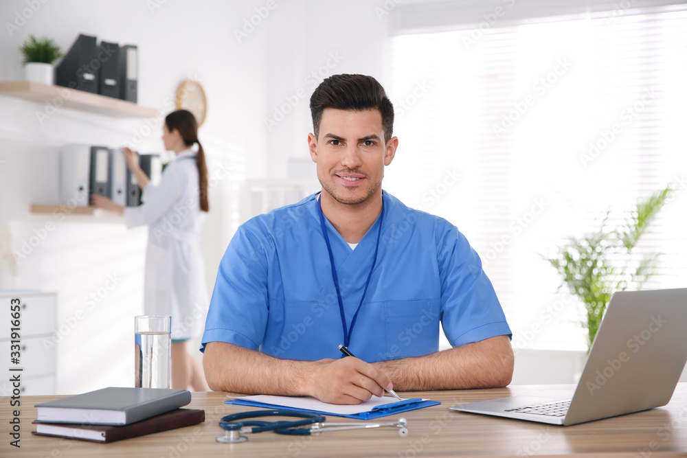 Portrait of male doctor at table in modern clinic Portrait of male doctor at table in modern clinic