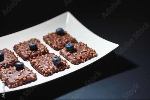 Chocolate dessert with nuts and fresh berries. Sweet snack for coffee biscuit in glaze and nut crumbs with fruit.