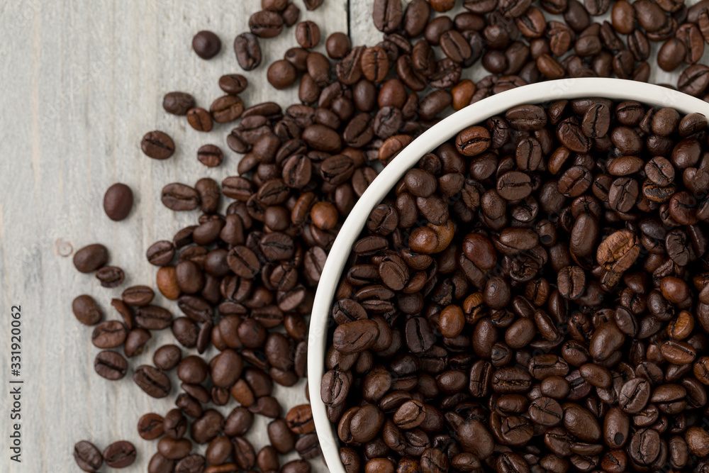 Top down shot of a bowl filled with freshly roasted arabica coffee beans on a rustic wood table Top down shot of a bowl filled with freshly roasted arabica coffee beans on a rustic wood table
