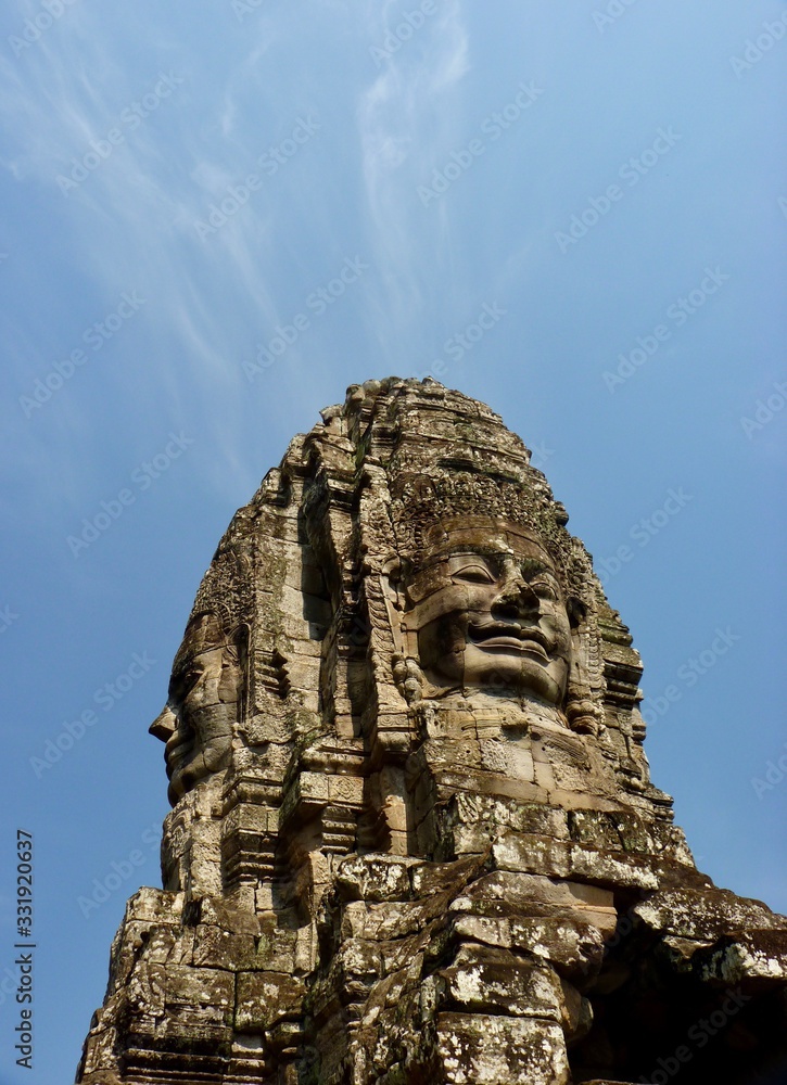Ruins of Angkor, face tower of Bayon temple against blue sky during evening, Angkor Wat, Cambodia