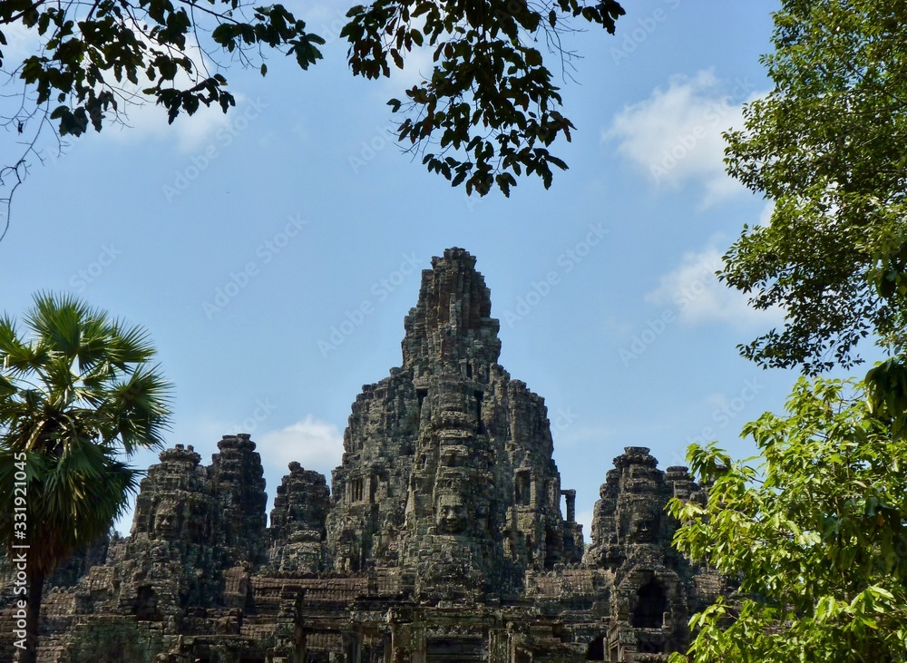 Ruins of Angkor, temple of Bayon with face towers, with trees, Angkor Wat, Cambodia Ruins of Angkor, temple of Bayon with face towers, with trees, Angkor Wat, Cambodia