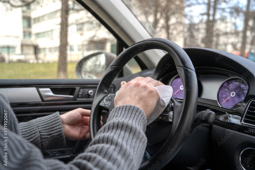 Man cleaning steering wheel of a car using antivirus antibacterial wet wipe (napkin) for protect himself from bacteria and virus. Man cleaning steering wheel of a car using antivirus antibacterial wet wipe (napkin) for protect himself from bacteria and virus.