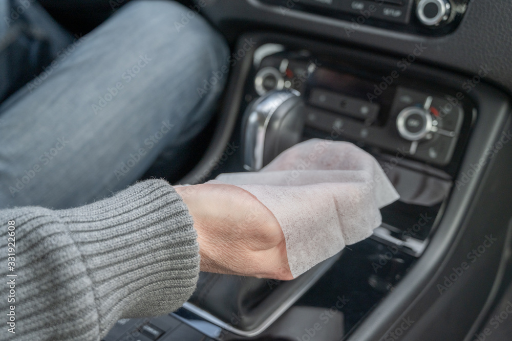 Man cleaning front dashboard of a car using antivirus antibacterial wet wipe (napkin) for protect himself from bacteria and virus.