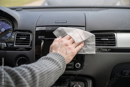 Принти на полотні Man cleaning front dashboard of a car using antivirus antibacterial wet wipe (napkin) for protect himself from bacteria and virus