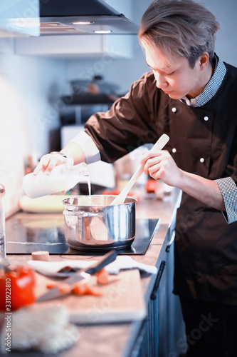 Asian cook in the kitchen prepares food in a cook suit