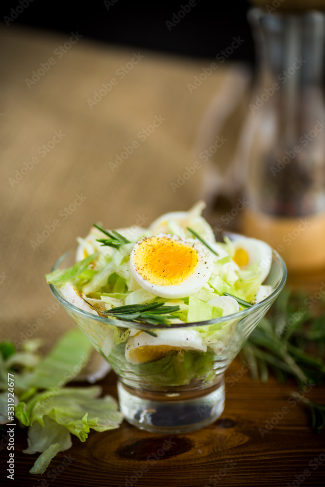 Fototapeta premium fresh spring salad with cabbage, lettuce and boiled eggs with rosemary and spices