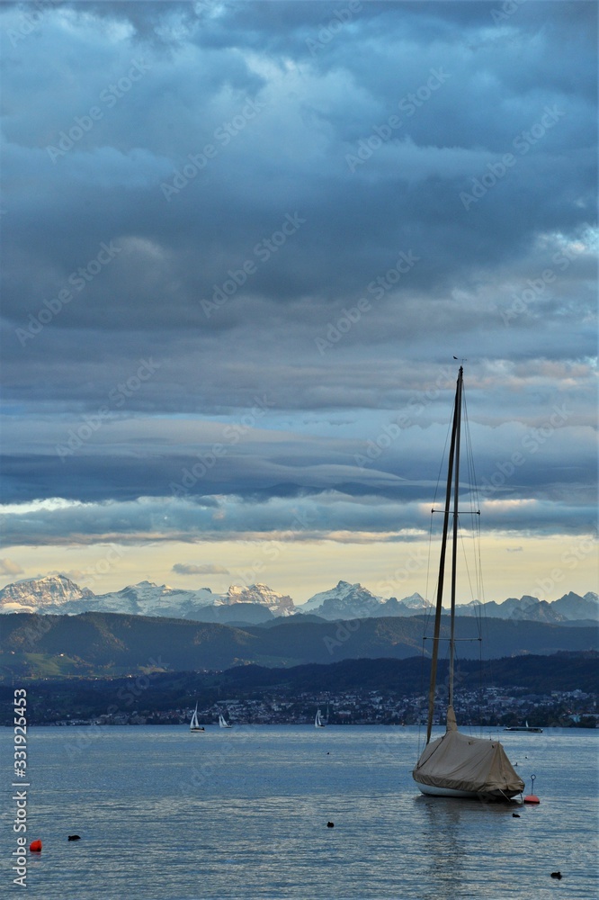 zurichsee with sailing ship in front of anchor and the alps in the evening mood