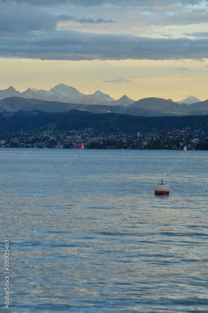 zurichsee with buoy and the alps in the evening mood