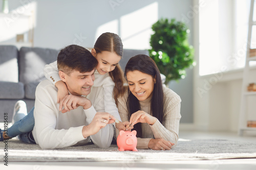 Stampa su Tela Happy family saves money in a piggy bank pig.