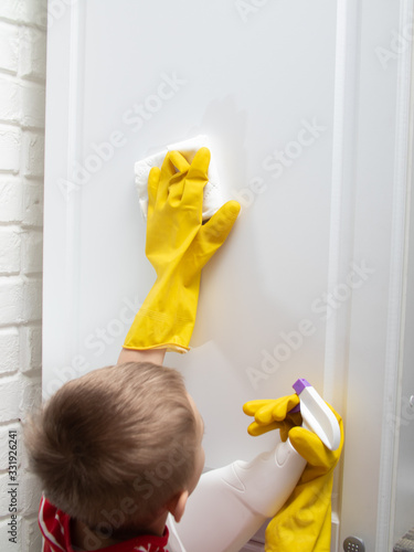a child in yellow rubber gloves is cleaning. the child wipes the furniture from dust and dirt. Step 4
