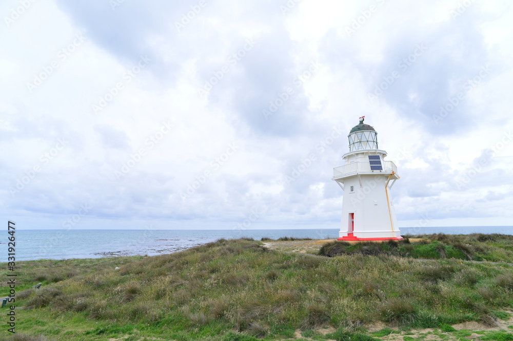 white lighthouse with red door in new zealand