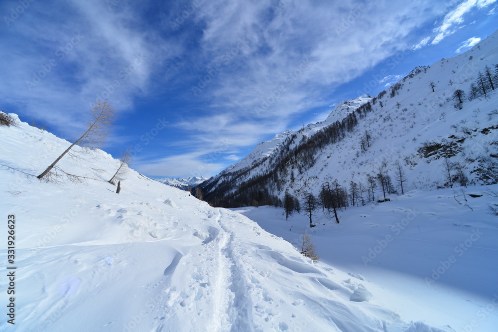 Snowy landscape in the Swiss mountains with a path in the snow with a blue sky