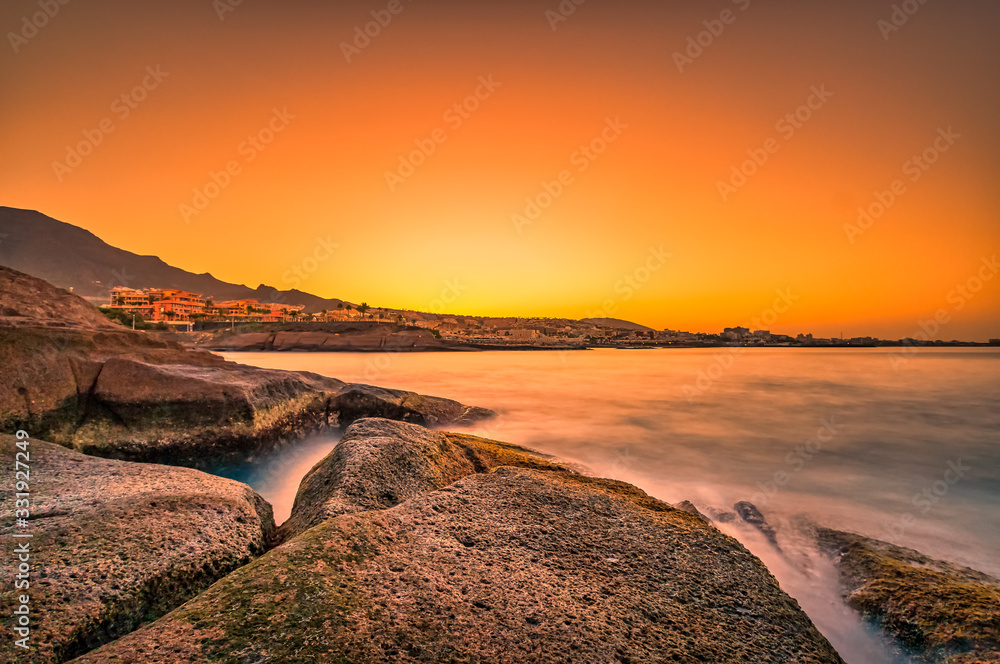 Warm colors at an impressive sunrise on stones nearby the sea.
