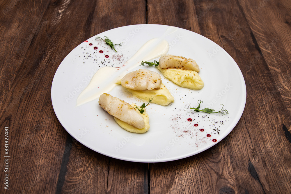 Halibut fillet with potato cream and cauliflower sauce. On a wooden table. Halibut fillet with potato cream and cauliflower sauce. On a wooden table.
