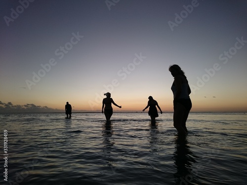 Sunset  with people walking in water 