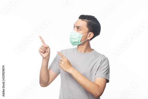 Young Asian Man wearing hygienic mask and pointing to copyspace, 2019-nCoV or coronavirus. Airborne respiratory illness such as pm 2.5 fighting and flu. Studio shot isolated on white background.