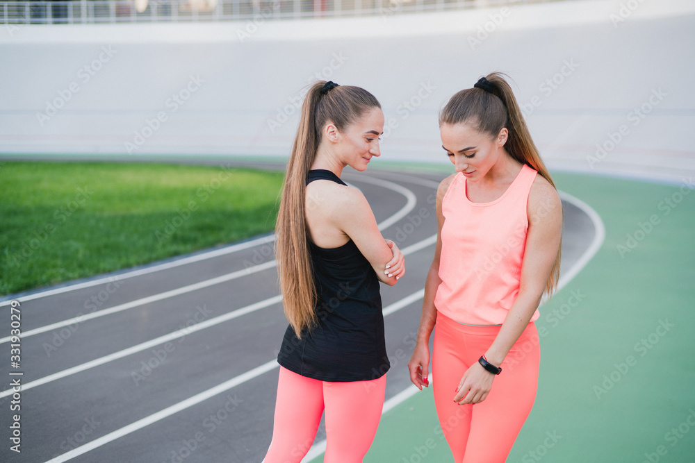 Sports and fitness outside the gym. Young fit women with perfect bodies in sportswear train together outdoors on playground. Sportive and healthy lifestyle, street work out, training, exercise concept