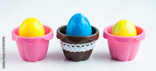 colorful Easter eggs in colored cupcake molds on a white background. Symmetrical image