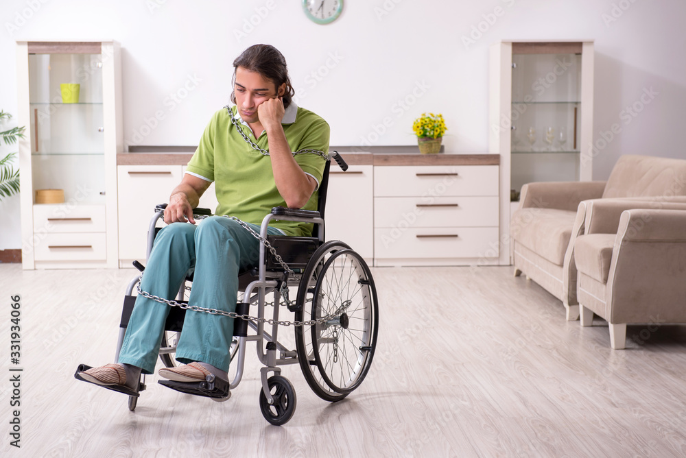 Young male invalid in wheel-chair suffering at home Young male invalid in wheel-chair suffering at home