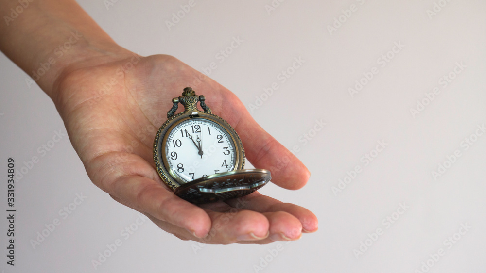 An old pocket watch on opening in a woman's hand shows 5 minutes to 12 o'clock. Negative space. Copy space for advertising. An old pocket watch on opening in a woman's hand shows 5 minutes to 12 o'clock. Negative space. Copy space for advertising.