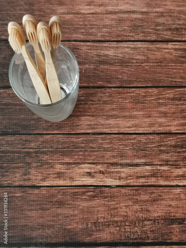 A family set of four wooden toothbrushes in a glass on wooden background with copy space 