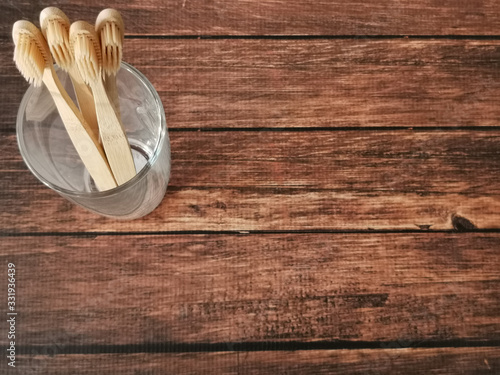 A family set of four wooden toothbrushes in a glass on wooden background with copy space 