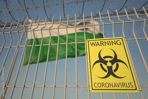 Biohazard coronavirus sign on the barbed wire fence near flag of Saxony, a state of Germany. COVID-19 quarantine related 3D rendering