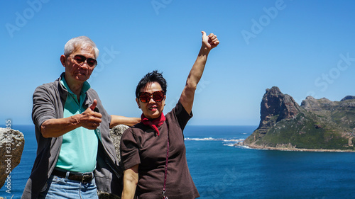 Asian senior couple travel anniversary trip in South Africa beautiful blue sea and sky beach coastline scene