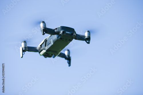 Fototapeta Naklejka Na Ścianę i Meble -  Four-propeller drone flying in nature against the blue sky. The maneuver.