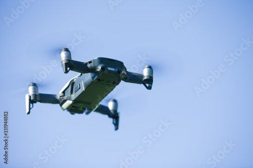 Fototapeta Naklejka Na Ścianę i Meble -  Four-propeller drone flying in nature against the blue sky. The maneuver.