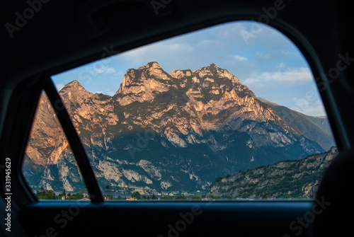 Car view of the mountains and the city of Riva del Garda, Italy. Alpine peaks on a sunny day.