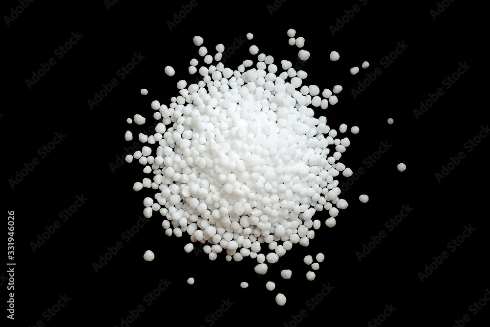 Urea fertilizer on a black background, top view. White mineral fertilizer balls - urea (carbamide). Urea nitrogen fertilizer on a black background.