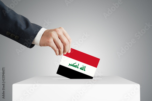 Man putting a voting ballot into a box with Iraq flag. photo